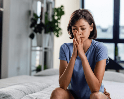 pensive-woman-with-hands-clasped-sitting-bed-thinking-something_637285-1505